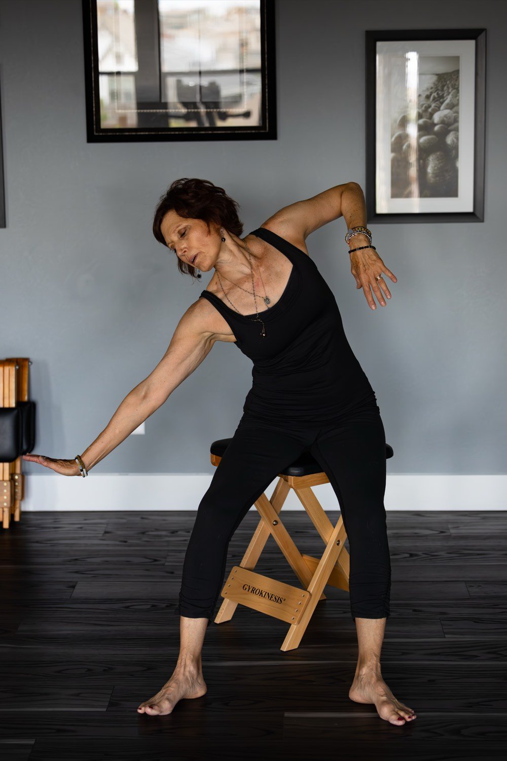 Deborah McBride performing a GYROKINESIS side bend on the studio stool at bodySpan