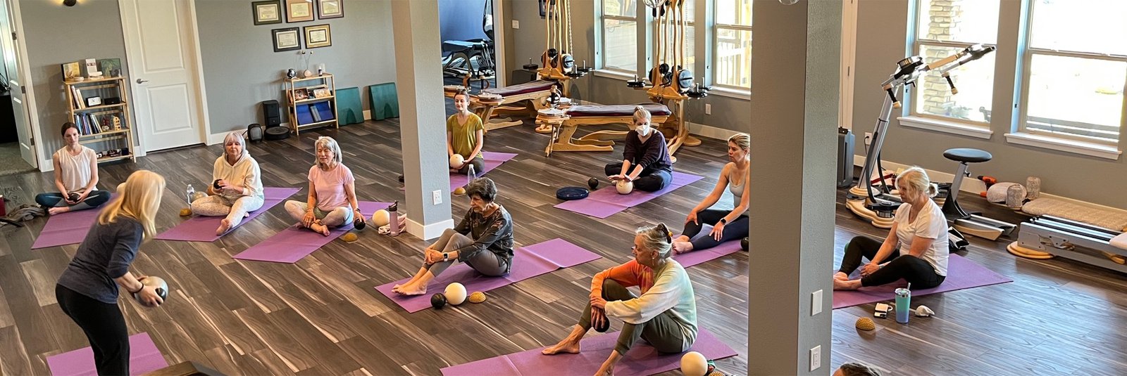 A Yamuna Body Rolling group class on mats at bodySpan Studio, led by an instructor with therapy balls